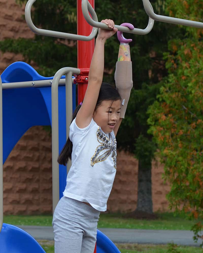 Picture of a girl hanging on monkey bars | Lawall Prosthetic & Orthotic Services