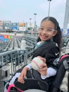 Girl in wheelchair holding a baseball